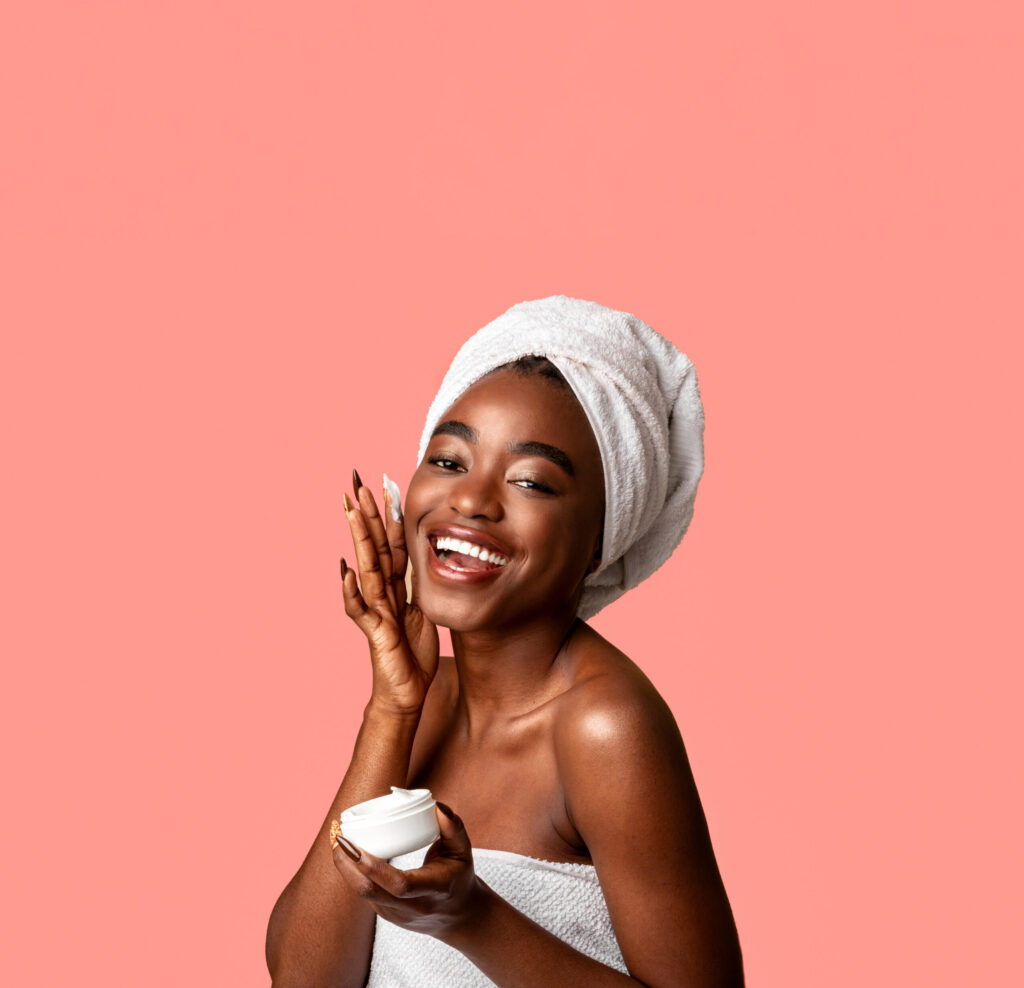 Beautiful young african american woman applying face cream