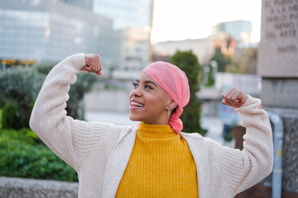 Young woman in pink scarf fights cancer disease and feels strong to overcome it. Concept: disease, fight, health care