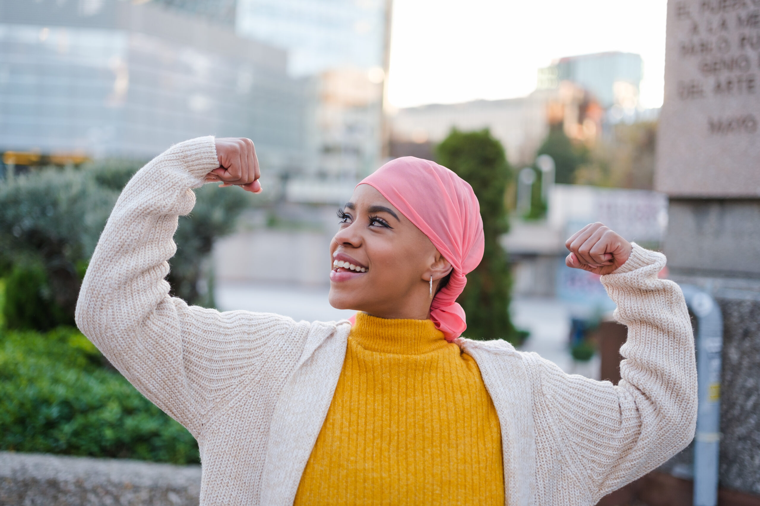 Young woman in pink scarf fights cancer disease and feels strong to overcome it. Concept: disease, fight, health care